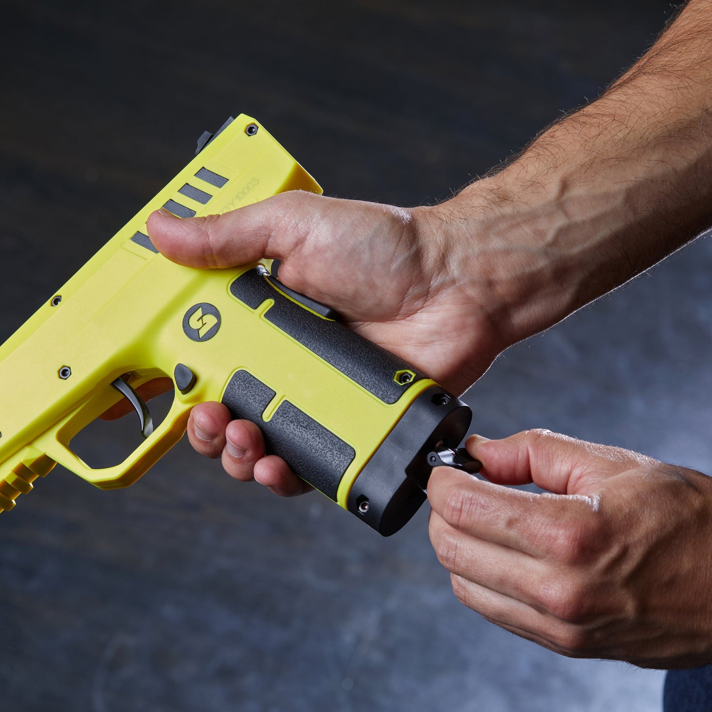 Someone loading 0.68 Caliber Home Defense Pepper Projectile Launcher – .68 caliber personal defense launcher designed for home use, featuring a ready-to-fire CO₂-powered firing mechanism that launches irritant pepper projectiles at defensive range, in gray background.
