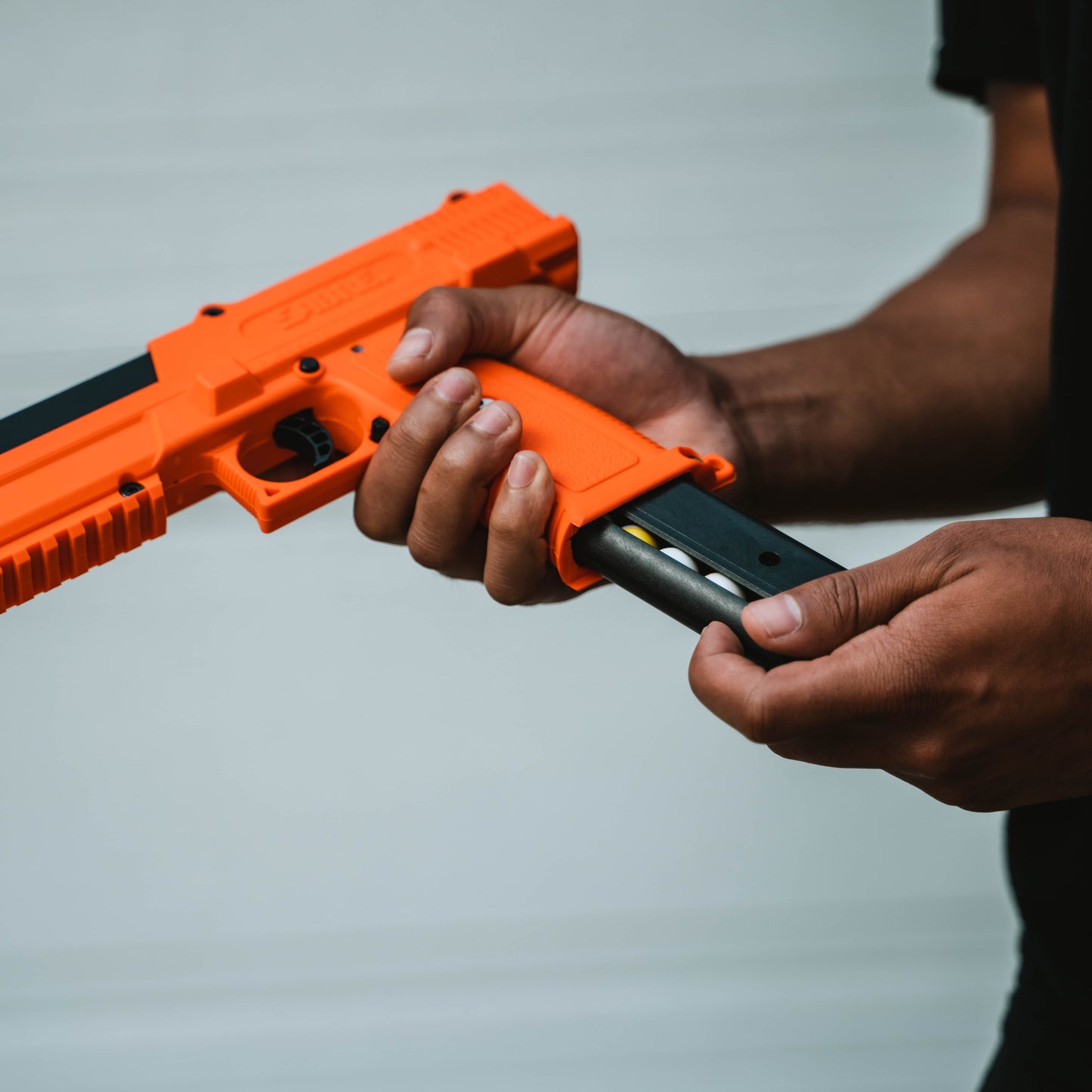 Someone loading 14 Inert 0.68 Cal Projectiles + 2 CO2 Cartridges – training kit designed for SABRE SLP1C and compatible 0.68 caliber launchers, including 14 inert powder projectiles and two 12g CO₂ cartridges for safe, practice use without active pepper irritants.