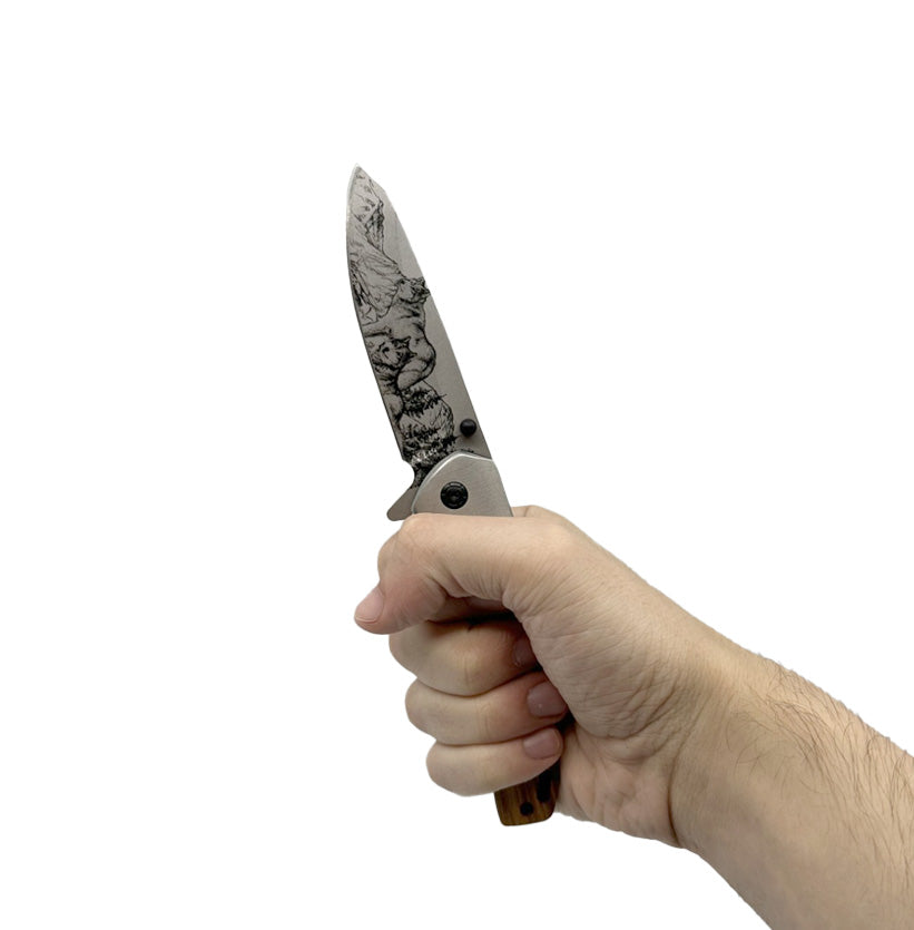 Someone holding 3.5″ Spring Assisted Folding Knife with Drop Point Blade – features a 3.5″ stainless steel drop point blade with decorative 3D‑printed wolf design, spring‑assist opening, ergonomic stainless steel and wood‑overlay handle (4.5″ closed), and pocket clip for everyday carry and tactical use, in white background.