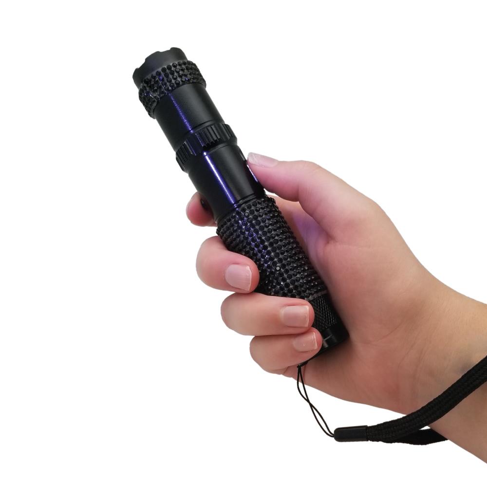 Someone holding Rhinestun 75,000,000 Stun Flashlight - stylish and powerful self-defense flashlight featuring rhinestone accents and a high-volage stun gun for discreet personal protection, in white background.