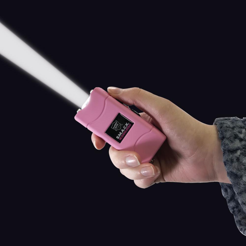 Someone holding SMACK 16,000,000 Stun Gun - ultra-compact and powerful self-defense device designed to fit on a keychain for convenient everyday carry, in black background.