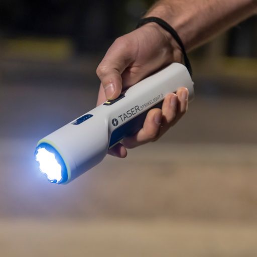 Someone holding TASER StrikeLight 2 Kit – versatile self-defense flashlight featuring a 700-lumen beam, built-in stun capability, audible arc warning, and USB-C charging for everyday protection, at night.