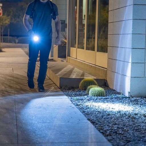 Someone walking with TASER StrikeLight 2 Kit – versatile self-defense flashlight featuring a 700-lumen beam, built-in stun capability, audible arc warning, and USB-C charging for everyday protection, at night.