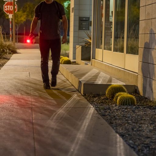 Someone walking with TASER StrikeLight 2 Kit – versatile self-defense flashlight featuring a 700-lumen beam, built-in stun capability, audible arc warning, and USB-C charging for everyday protection, at night.