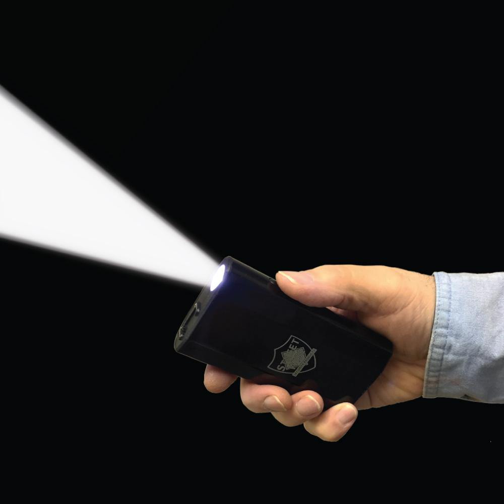 Someone holding 3-N-1 28,000,000* Stun Gun - multifunctional self-defense device combining a stun gun, flashlight, and safety alarm for maximum personal protection, in black background.
