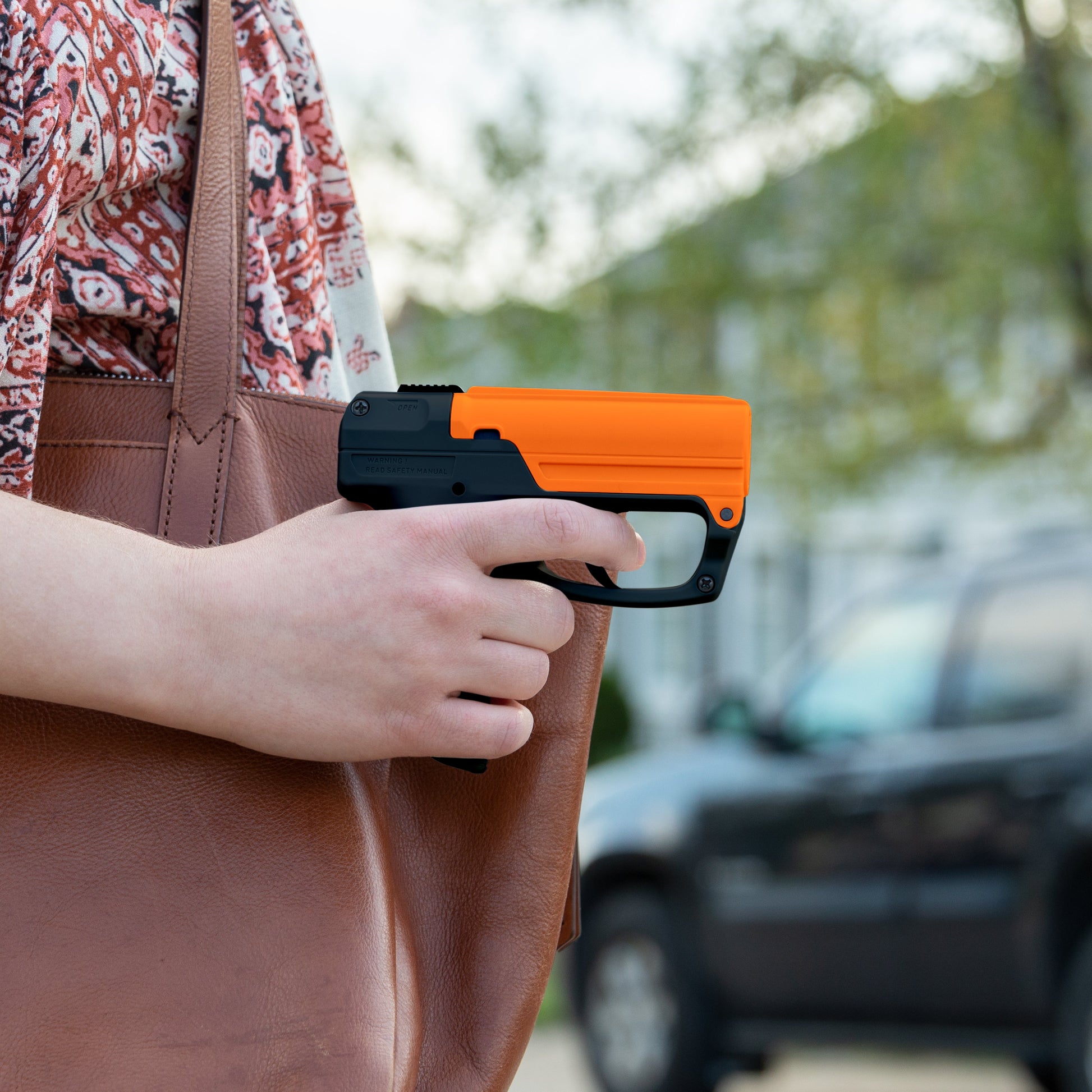 Someone holding Aim and Fire Pepper Gel with Trigger and Grip Deployment – pistol-style pepper gel launcher featuring a 15-foot range, 13 bursts per cartridge, and a grip safety to prevent accidental discharge.