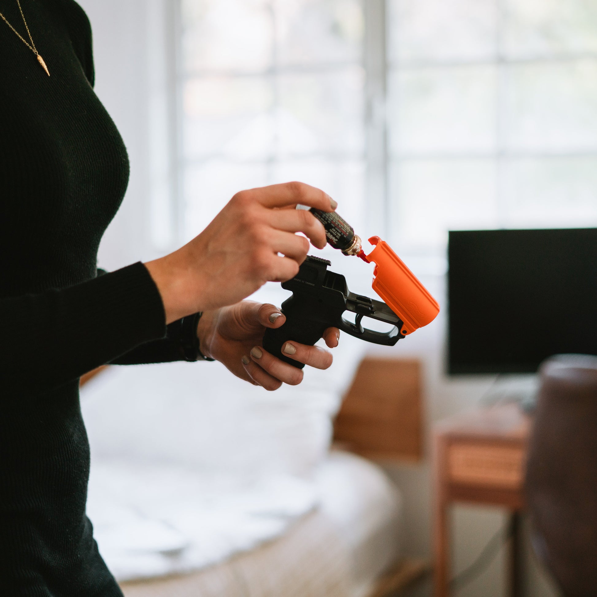 Someone loading Aim and Fire Pepper Gel with Trigger and Grip Deployment – pistol-style pepper gel launcher featuring a 15-foot range, 13 bursts per cartridge, and a grip safety to prevent accidental discharge.