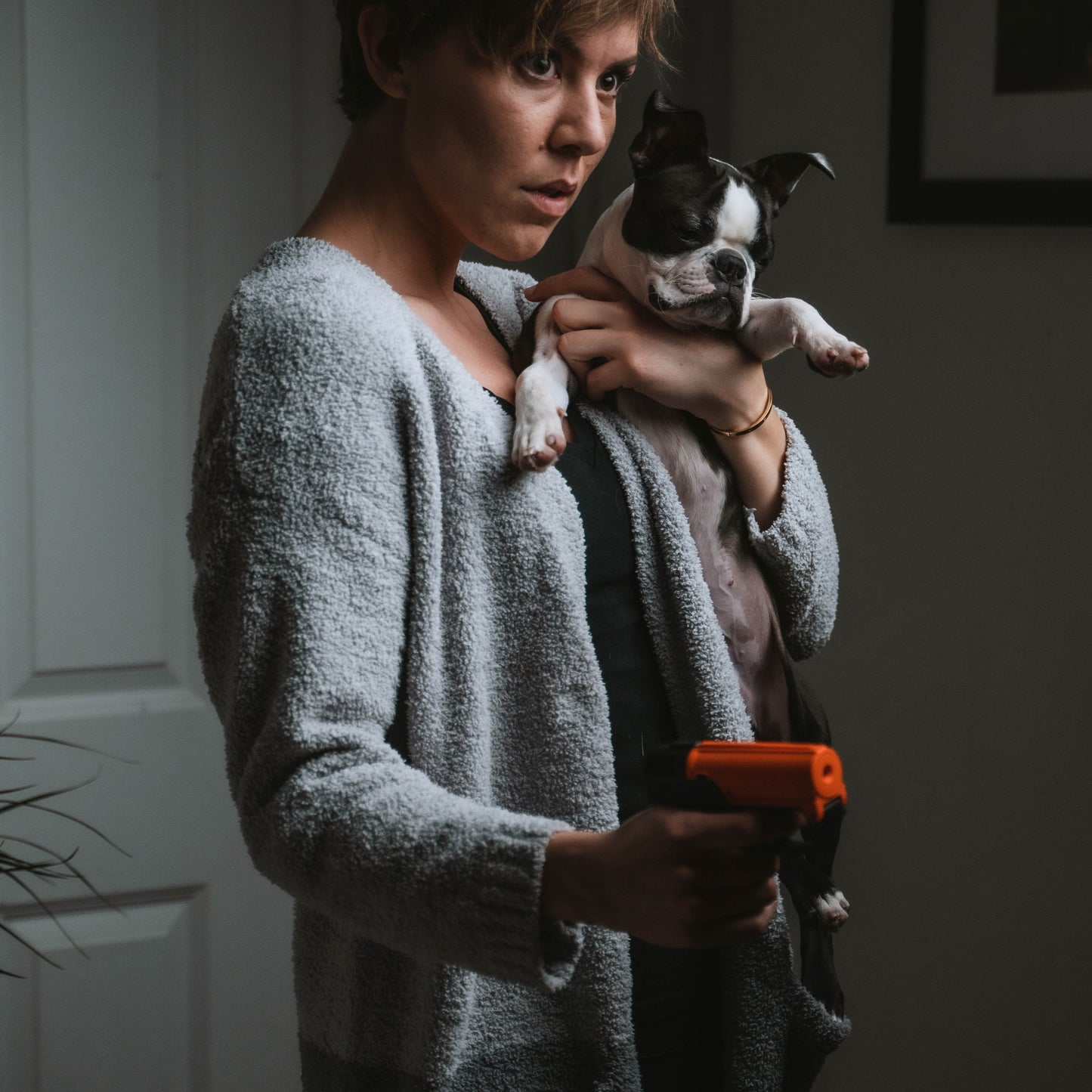 Someone holding Aim and Fire Pepper Gel with Trigger and Grip Deployment – pistol-style pepper gel launcher featuring a 15-foot range, 13 bursts per cartridge, and a grip safety to prevent accidental discharge, at night while holding a dog.