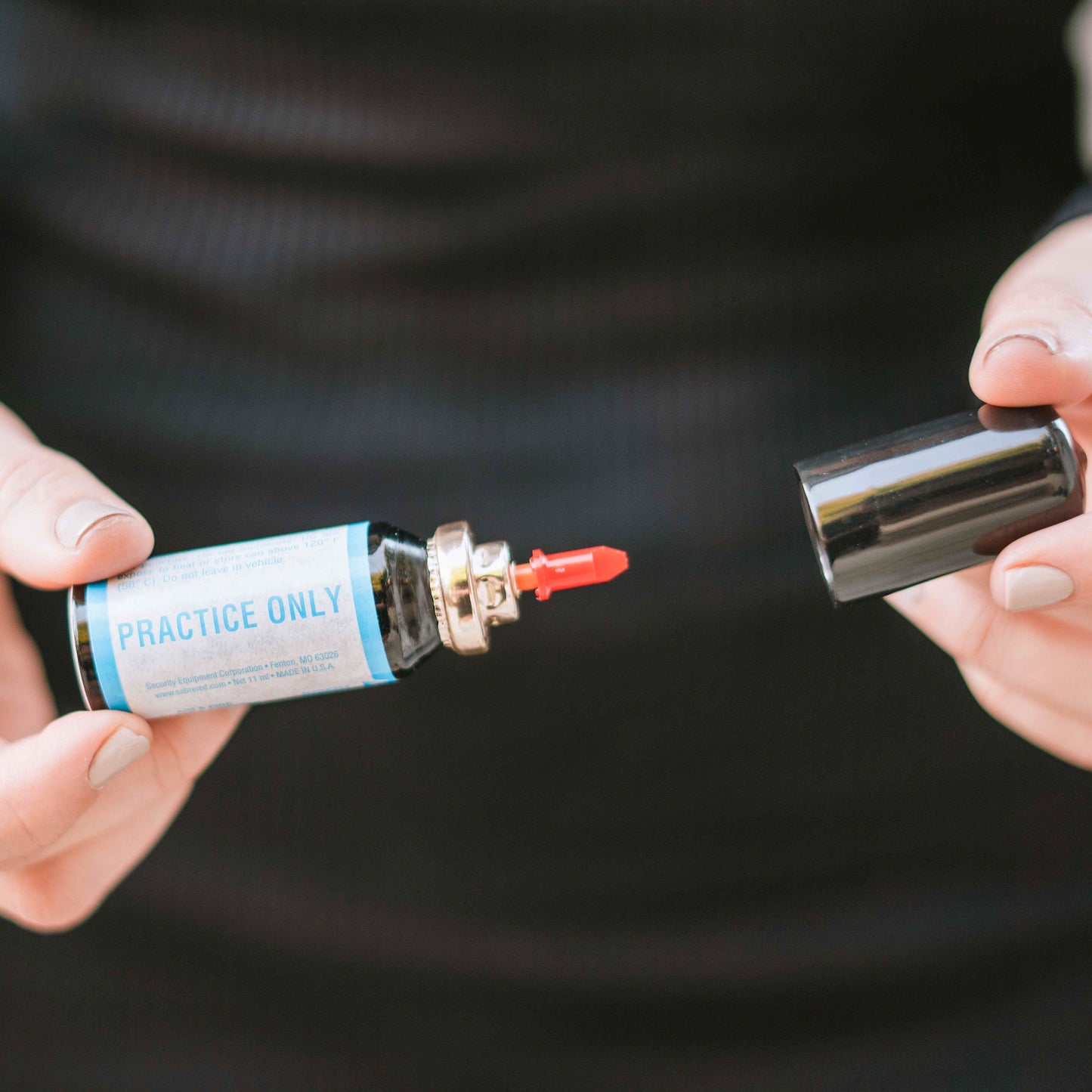 Someone opening cartridge of Aim and Fire Pepper Gel with Trigger and Grip Deployment – pistol-style pepper gel launcher featuring a 15-foot range, 13 bursts per cartridge, and a grip safety to prevent accidental discharge.