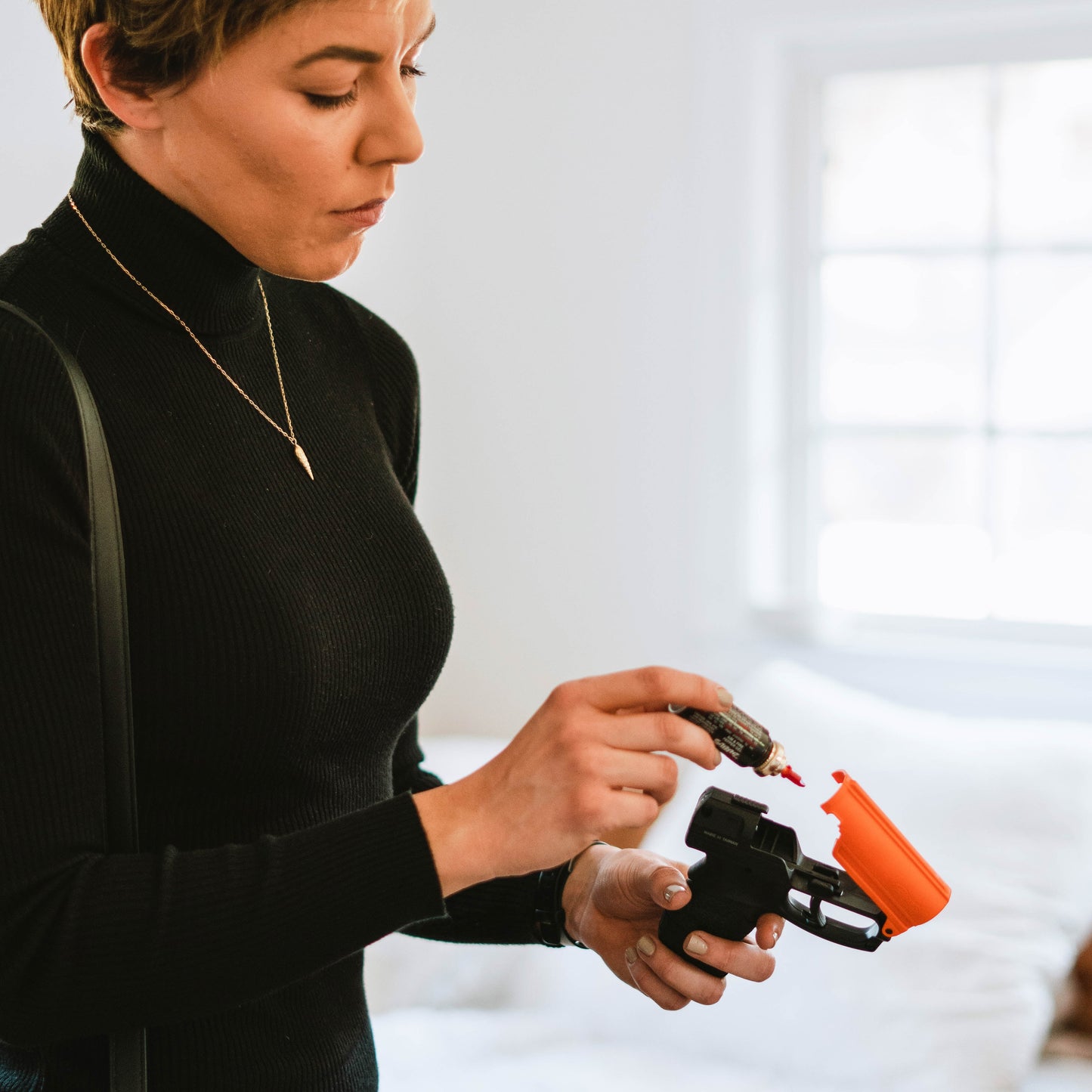 Someone loading Aim and Fire Pepper Gel with Trigger and Grip Deployment – pistol-style pepper gel launcher featuring a 15-foot range, 13 bursts per cartridge, and a grip safety to prevent accidental discharge.