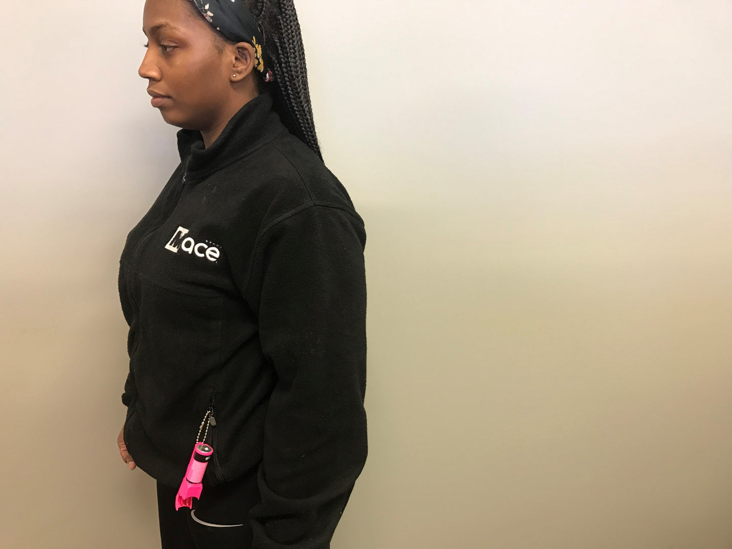 Someone carrying Mace Pocket Model Stream Pepper Spray – compact self-defense spray with a focused stream pattern delivering up to 10 ft of range, flip-top safety cap, finger-grip design, and UV dye for attacker identification, in tan background.