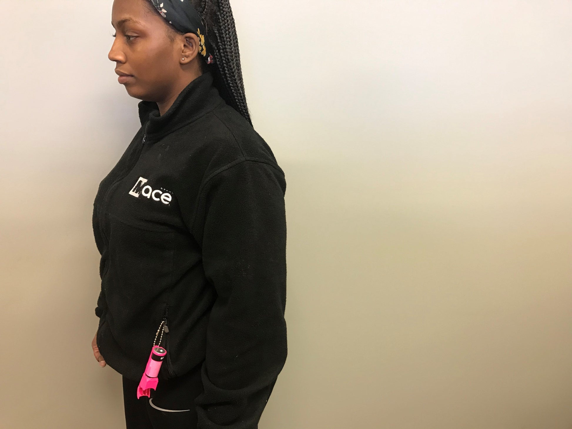 Someone carrying Mace Pocket Model Stream Pepper Spray – compact self-defense spray with a focused stream pattern delivering up to 10 ft of range, flip-top safety cap, finger-grip design, and UV dye for attacker identification, in tan background.