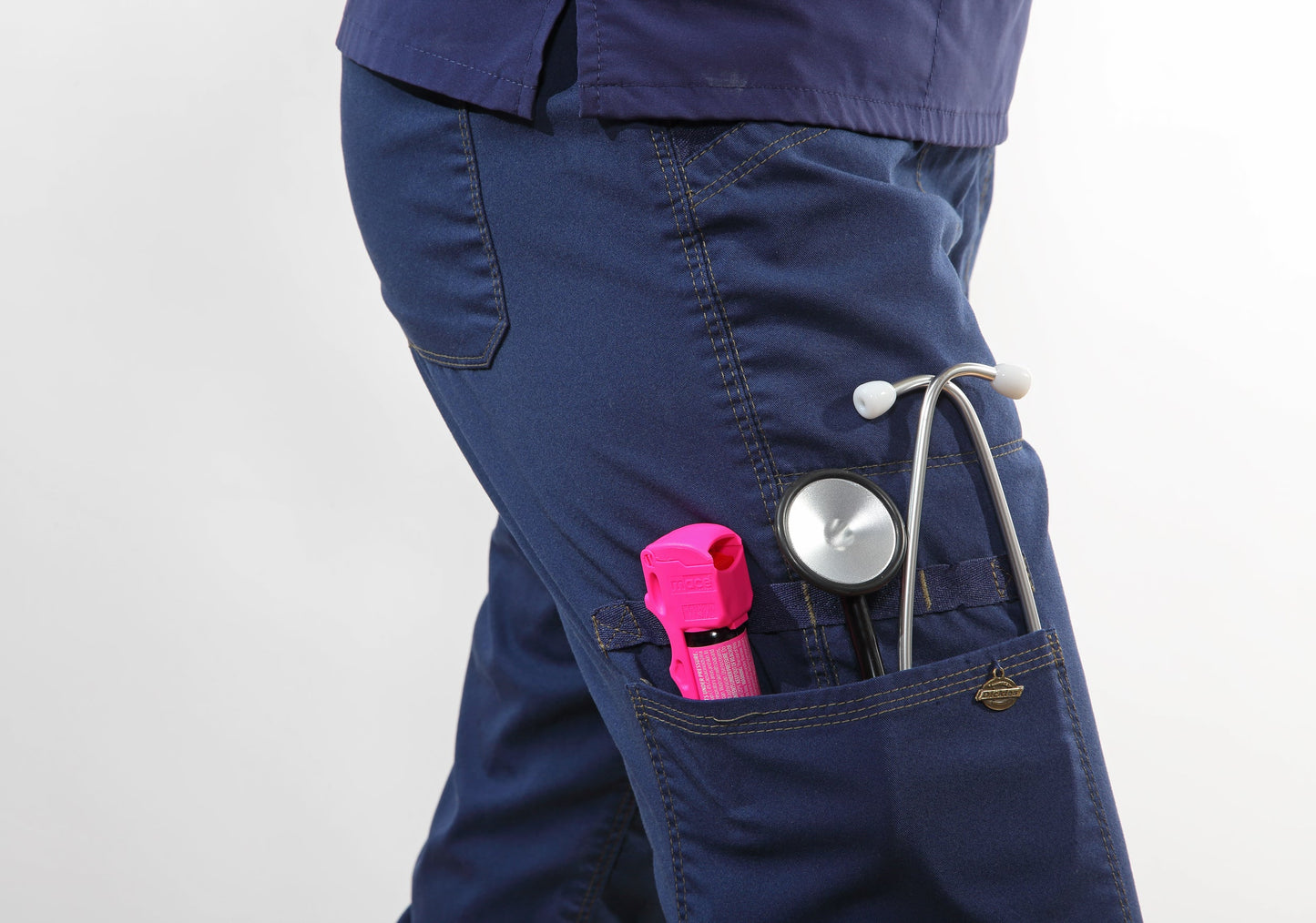 Someone carrying Mace Pocket Model Stream Pepper Spray – compact self-defense spray with a focused stream pattern delivering up to 10 ft of range, flip-top safety cap, finger-grip design, and UV dye for attacker identification, in cargo pants and white background.