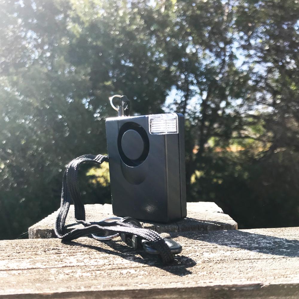 Compact personal door alarm with built-in LED light, ideal for home or travel security, in white background.