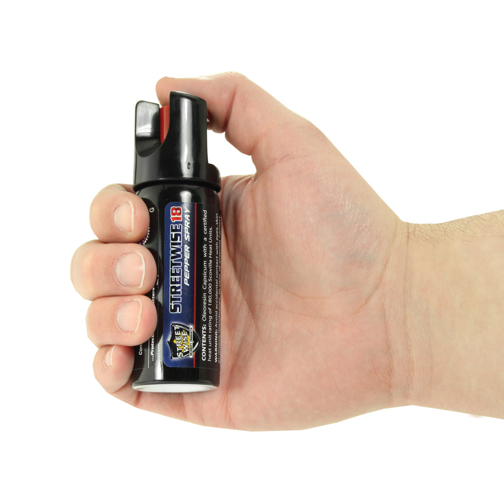 Someone holding Streetwise 18 Stream Pepper Spray with Twist Lock Safety Cap on white background.
