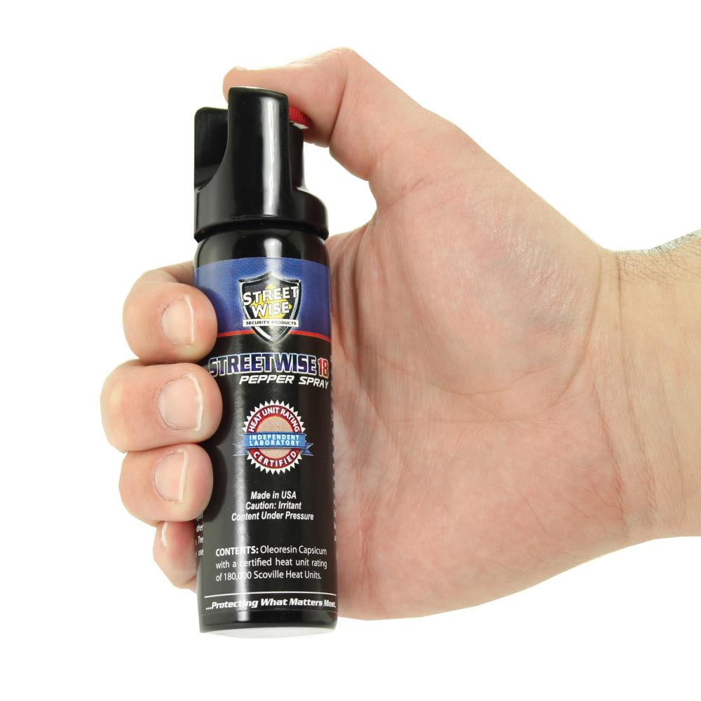 Someone holding Streetwise 18 Stream Pepper Spray with Twist Lock Safety Cap on white background.